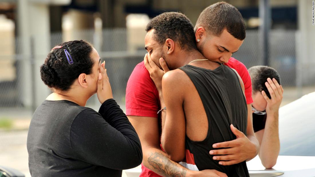 Friends and family members embrace outside the Orlando Police headquarters.