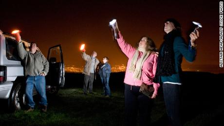 UFO spotters use flashlights to look for stars and aliens in the night sky in South Wales, Australia, in 2008. 