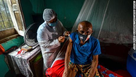 A man is vaccinated against Covid-19 by a health worker in a remote area of Moju, Para state, Brazil on April 16, 2021.