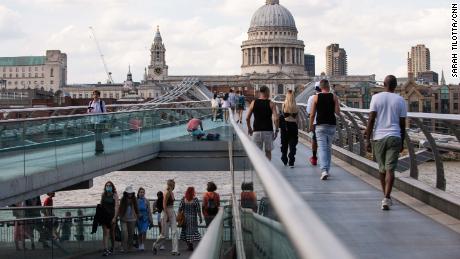 Pedestrians, some in masks, cross London&#39;s Millennium footbridge. The British government didn&#39;t make face coverings compulsory indoors or on public transport until last summer, and masks have never been mandated outdoors.