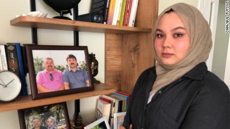 Dilsar Ablimit, 21, em sua casa na Turquia em junho, com fotos de seu pai e tio antes de ser preso.