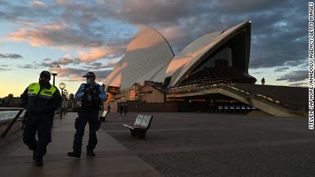 Police officers walk past the Sydney Opera House during the first day of lockdown on Saturday.