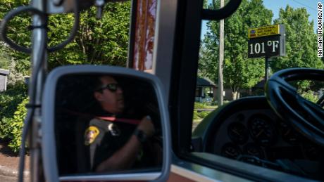 Cody Miller, with the Salem Fire Department, waits near a digital sign tracking the day&#39;s temperatures as parts of Oregon bake in a heat wave Saturday.