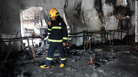 A firefighter investigates the fire scene at a martial arts school in China&#39;s Henan on June 25.