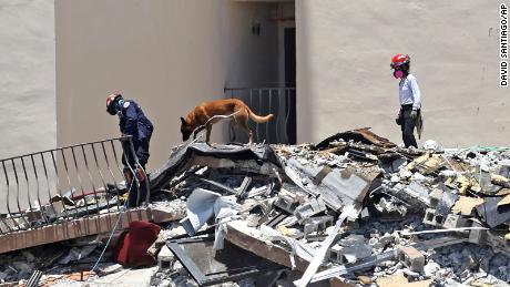 Search and rescue personnel search for survivors through the rubble with their dogs at the Champlain Towers South in Surfside, Fla., Sunday, June 27, 2021. 