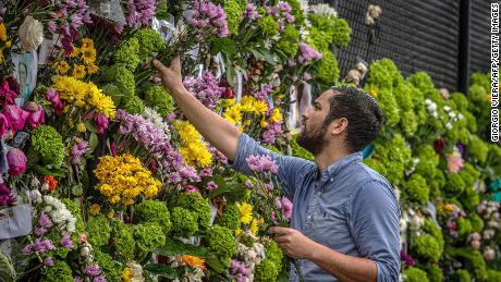 Leo Souto adds flowers to a memorial featuring photos of some of those lost in the partially collapsed Champlain Towers South building. 
