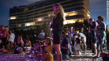 People join together in a community twilight vigil on the beach for those lost and missing during the partially collapsed Champlain Towers South condo building Monday.