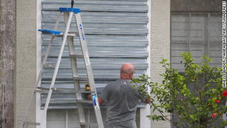 A Tampa resident covers his windows with hurricane shutters in preparation for Hurricane Elsa Tuesday.