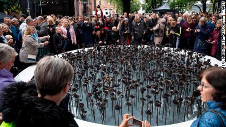 People stand next to the &quot;Iron roses&인용; memorial outside Oslo Cathedral on September 28, 2019, to commemorate the 77 victims of Anders Behring Breivik&#39;s attacks.