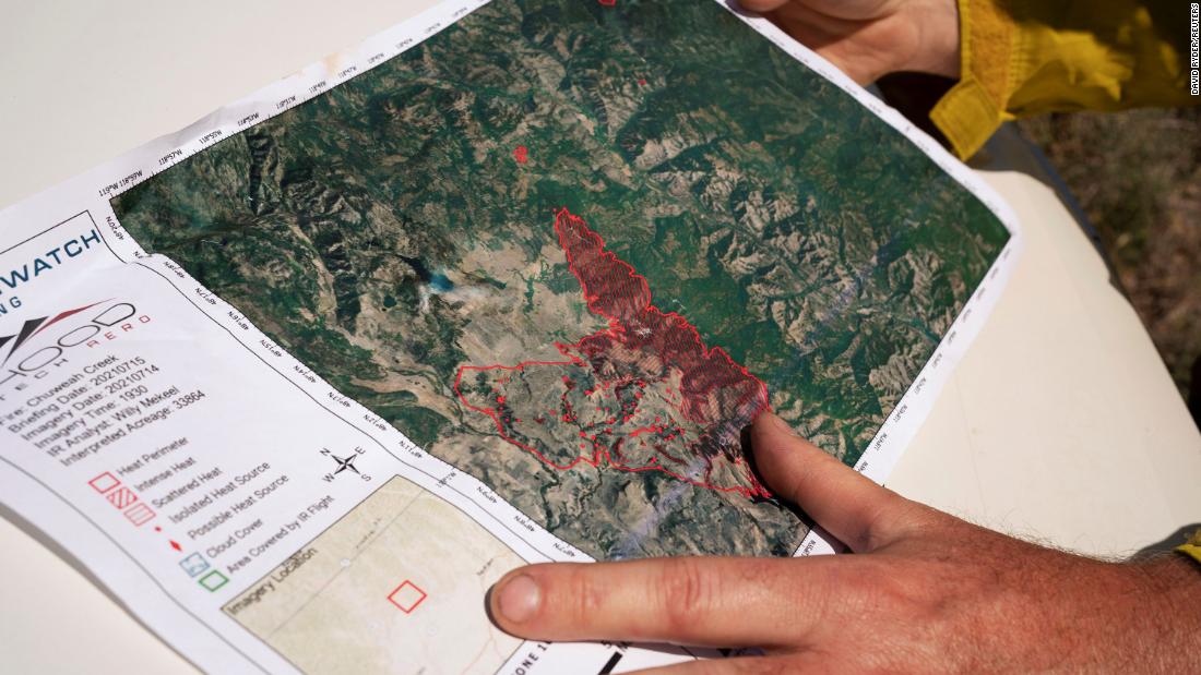 Miembro del equipo de gestión de incidentes del noroeste 12 sostiene un mapa del Chuweah Creek Fire cuando los incendios forestales devastaron Nespelem, Washington, en julio 16.