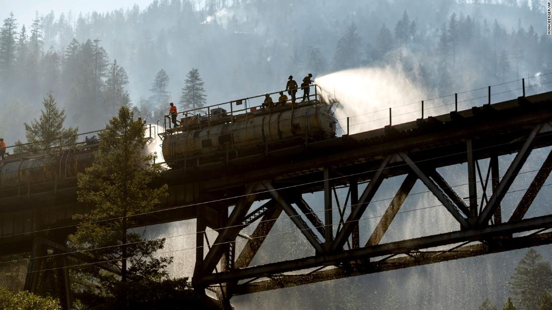 Firefighters spray water from the Union Pacific Railroad&#39;s fire train while battling the Dixie Fire in California&#39;s Plumas National Forest on July 16.