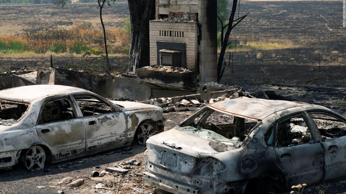 Burned cars sit outside a home that was destroyed by the Chuweah Creek Fire in Nespelem, 华盛顿州.