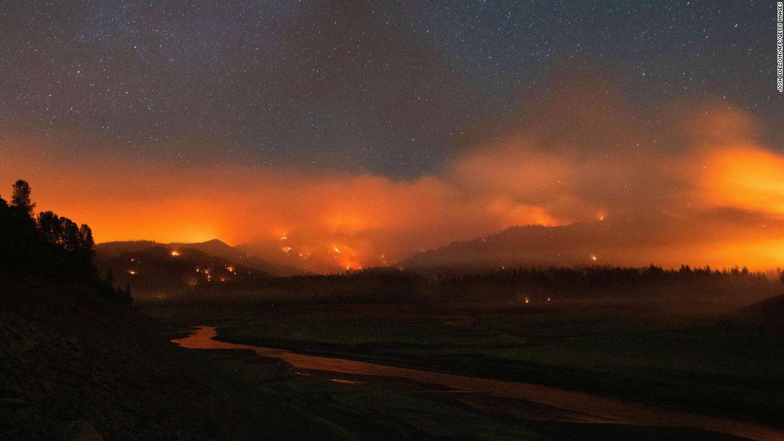 In this long-exposure photograph, taken early on July 2, flames surround a drought-stricken Shasta Lake during the Salt Fire in Lakehead, Kalifornië.