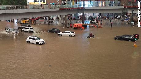 People stranded in flood waters along a street following heavy rains in Zhengzhou, Cina, a luglio 20.