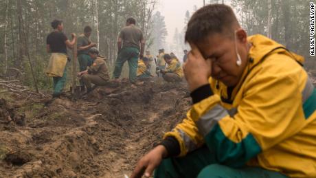 A equipe de proteção da floresta de Yakutlesresurs descansa enquanto cava um fosso de incêndio para conter um incêndio fora da vila de Magaras em Yakutia.