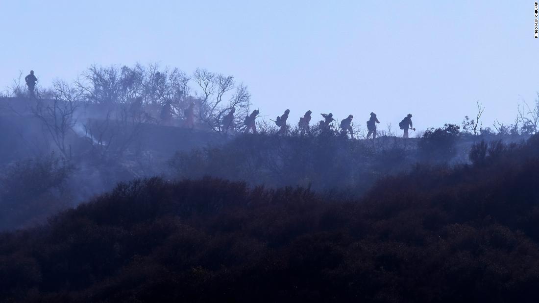 Firefighters walk near a wildfire in Topanga, Kalifornië, op Julie 19.