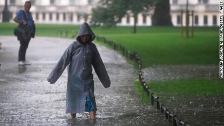 A pedestrian walks through a flooded area in St James&#39;s Park in central London on Sunday.