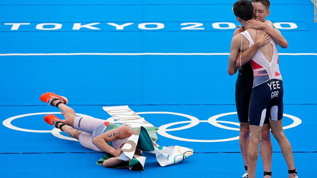 Norway&#39;s Kristian Blummenfelt lies on the ground wrapped in finish-line tape after he won the triathlon on July 26. On the right, silver medalist Alex Yee of Great Britain hugs bronze medalist Hayden Wilde of New Zealand.