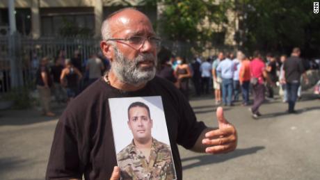 Elias Maalouf está em frente ao Ministério da Justiça de Beirute segurando uma foto de seu filho George, que foi morto na explosão.