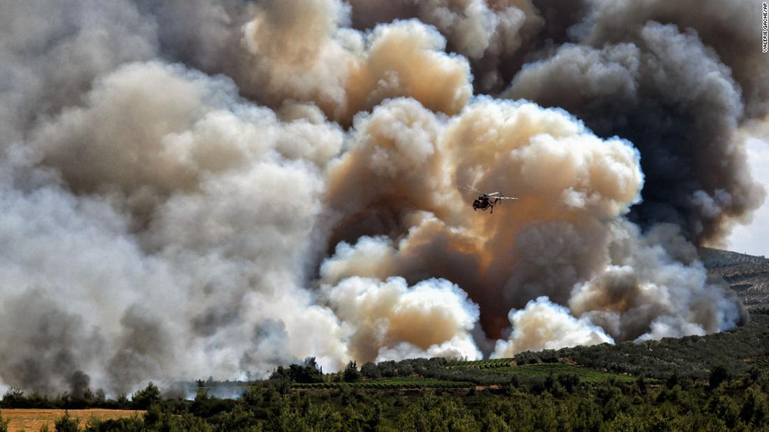A firefighting helicopter passes in front of a cloud of smoke from a forest fire near Spathovouni village, southwest of Athens, 希腊, 在七月 23.