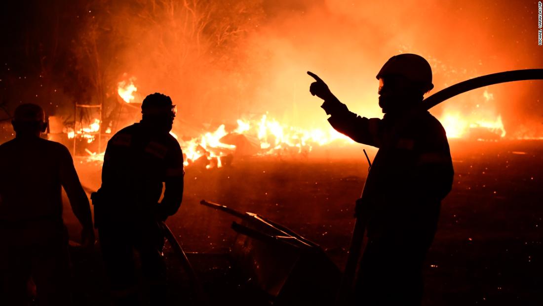 Firefighters work as a house burns in the Adames area of northern Athens on August 3.