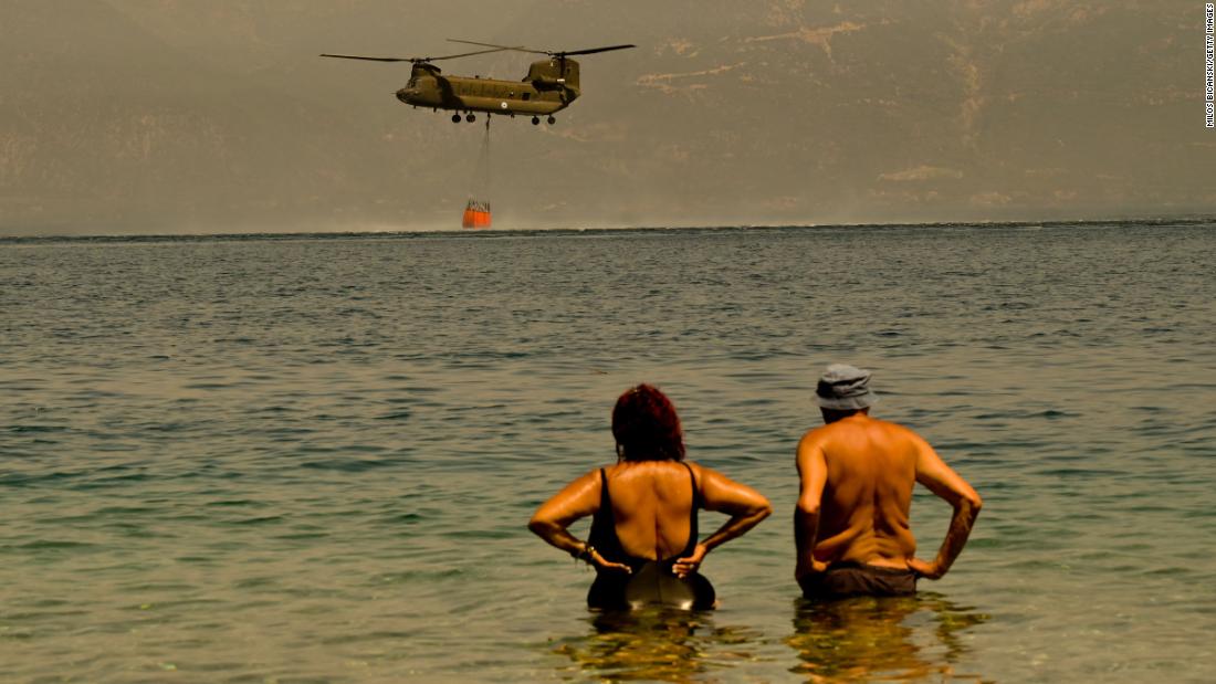 Local residents watch as a Greek army helicopter collects water to tackle a wildfire near the village of Lambiri, 希腊, 在八月 1.