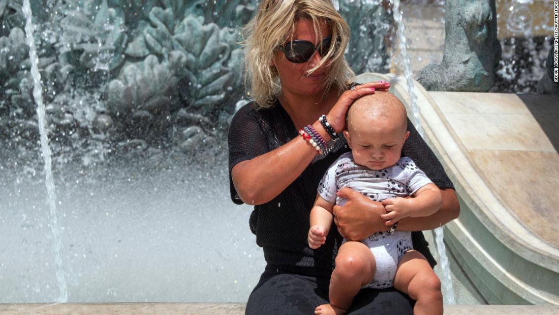 A woman pours water over a baby&#39;s head at a fountain in Skopje, North Macedonia, as temperatures reached over 40 摄氏度 (104 华氏度) 在八月 2. 