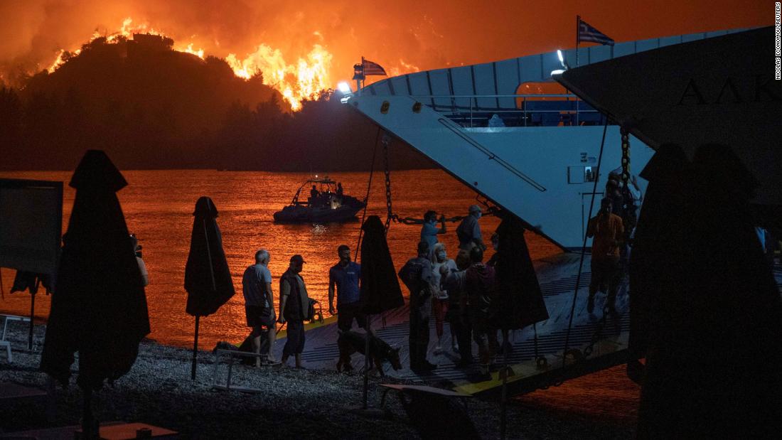 People are evacuated on a ferry as a wildfire burns in Limni, 希腊, 在八月 6.