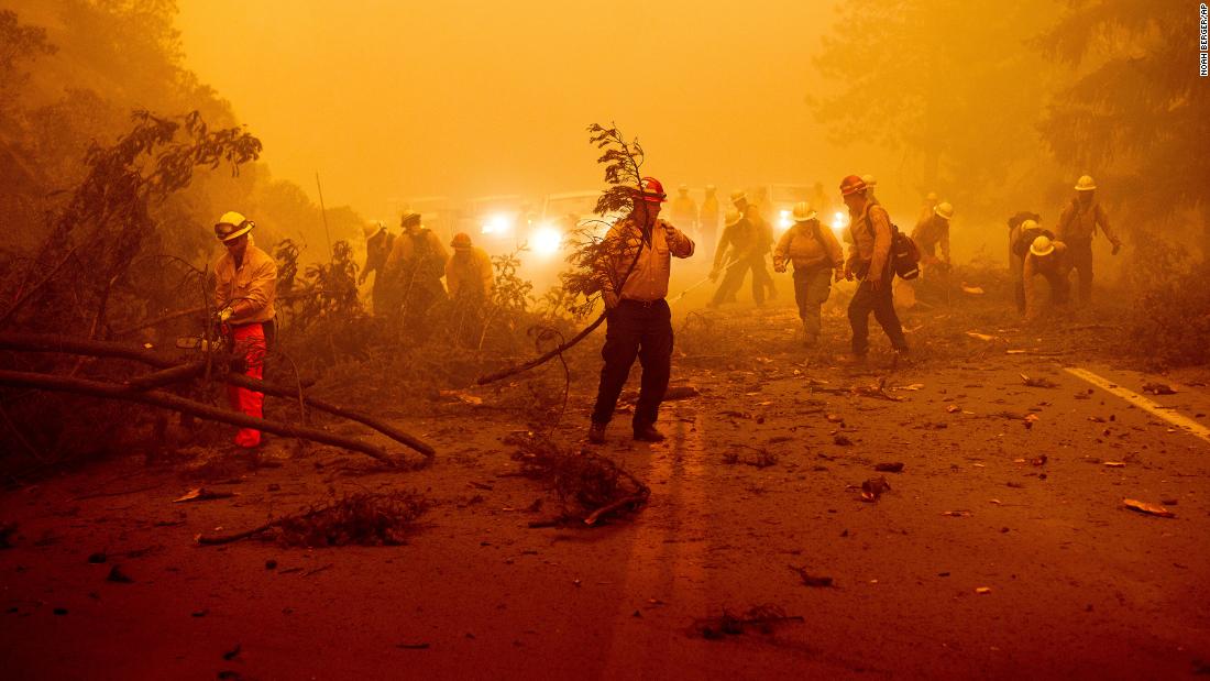 Firefighters battling the Dixie Fire clear a fallen tree from a roadway in Plumas County, Kalifornië, op Augustus 6.