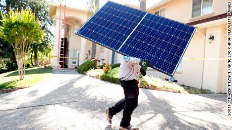 A Sunrun employee carries a solar panel to an installation at a home in California in May.