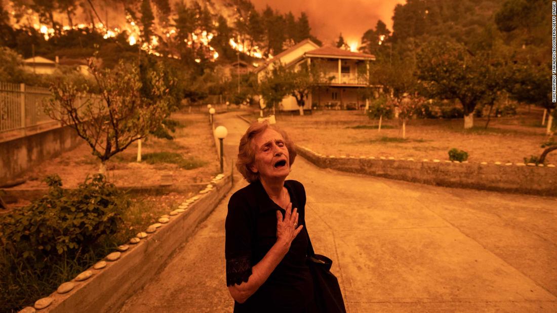 A resident reacts as a wildfire approaches her house in the Greek village of Gouves, on the island of Evia, 在八月 8.