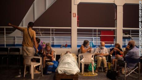 Idosos são vistos em cadeiras e camas improvisadas a bordo da balsa no porto da vila de Pefki durante um incêndio na vila de Pefki, Eubeia.