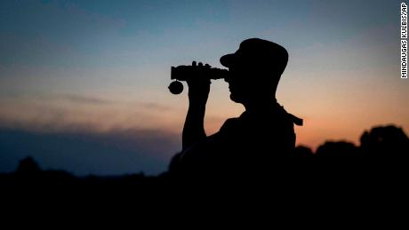 A member of the Lithuania State Border Guard Service looks through binoculars as he patrols on the border with Belarus, near the village of Purvenai, Lithuania.