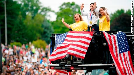 Suni Lee, center, waves from a St. Paul fire truck with her mom Yeev Thoj, left, and sister Shyenne Lee as fans cheer for her in a parade on August 8, 2021, in St. Paul, Minnesota. 