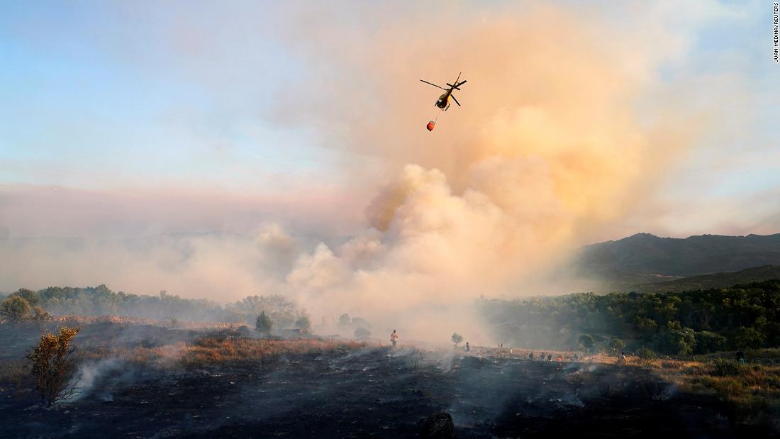 A helicopter drops water as a wildfire burns in the village of Navalmoral, 西班牙, 在八月 16. 