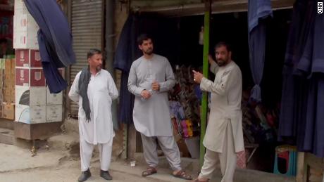 Os homens estão diante de uma loja de roupas no centro de Cabul.  O dono da loja disse à CNN que tem vendido significativamente mais burcas nos últimos dias.