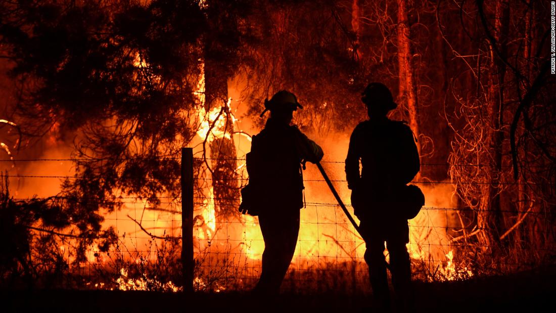 Los bomberos rocían agua sobre los árboles quemados por el incendio de Dixie cerca de Janesville, California, en Agosto 17.