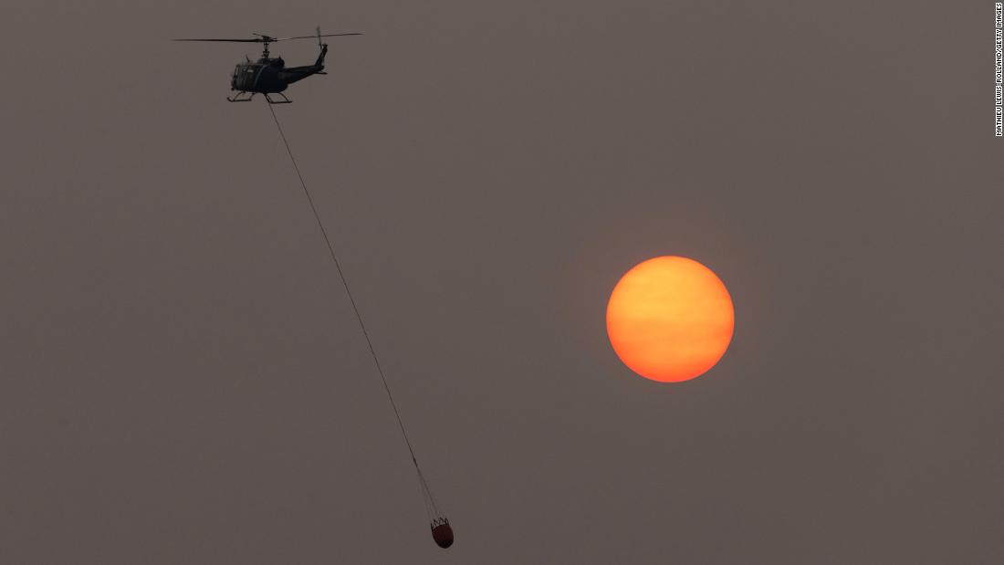 A firefighting helicopter flies in front of the sun, which was shrouded in thick wildfire smoke near Lakeview, 俄勒冈州, 在八月 15.