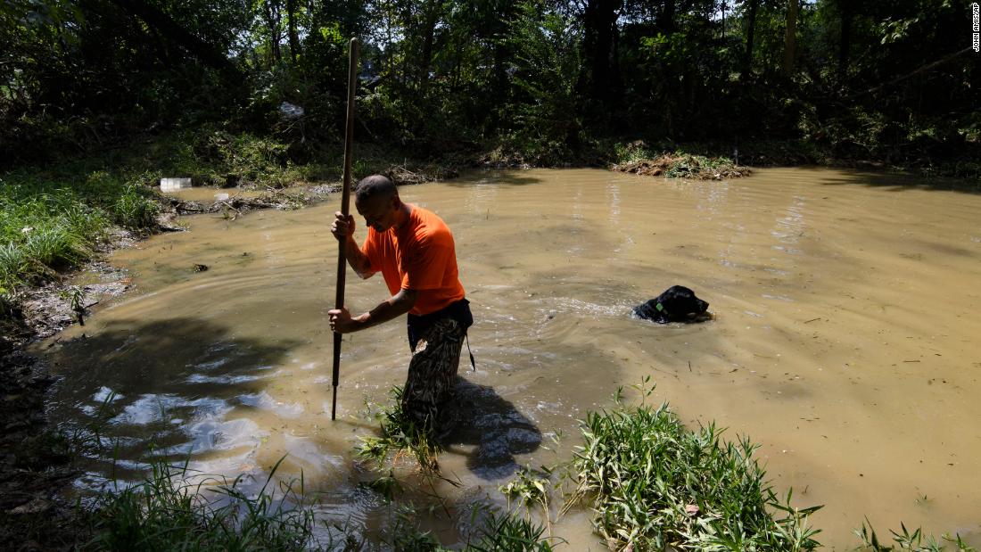 Dustin Shadownes of the Ashland City Fire Department searches a creek for missing persons with a cadaver dog on August 23, in Waverly, Tennesse.