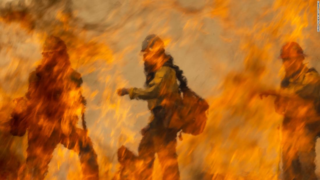 Los bomberos son vistos detrás de las llamas de un incendio que estaban preparando para combatir el incendio francés cerca de Wofford Heights..