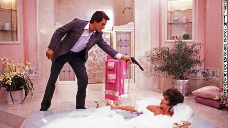 Joan Collins (Alexis) and Michael Nader (Dex Dexter) in a bathroom scene on the set of TV series &quot;Dynasty&quot; where Dex threatens Alexis with a gun while she is taking a bubble bath. In Hollywood, California, June 1988.