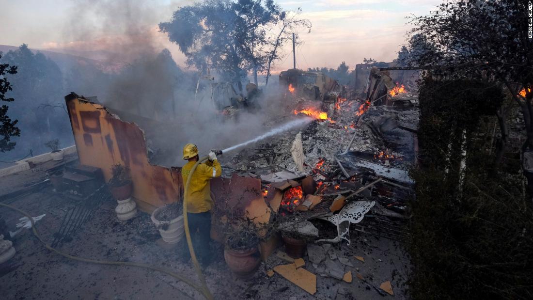 A firefighter tries to extinguish flames at a burning house as the South Fire burned in Lytle Creek, Kalifornië, op Augustus 25.