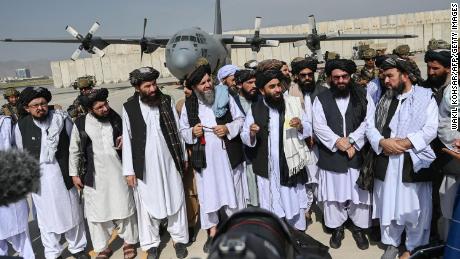 Taliban spokesman Zabihullah Mujahid (center, with shawl) speaks to the media at the airport. 