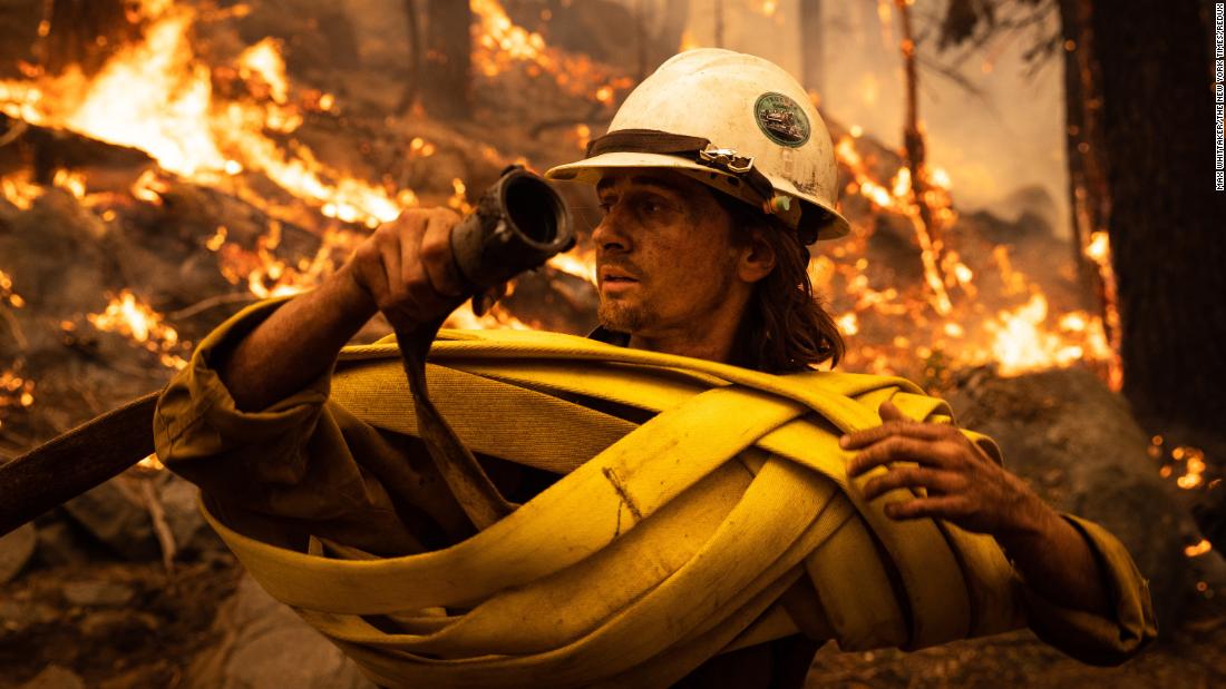 A firefighter winds up hose at a spot fire near Meyers, Kalifornië, op Augustus 30.