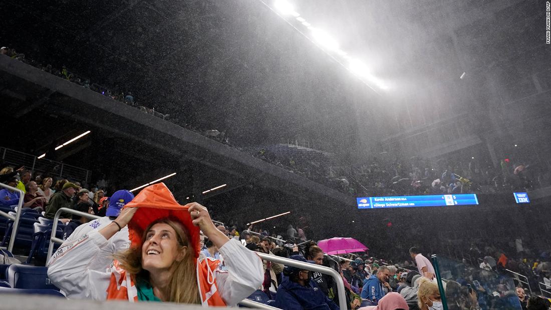 A tennis fan covers herself from rain as she attends a match at the US Open in New York on September 1. A second-round singles match between Kevin Anderson and Diego Schwartzman was halted early in the second set as &lt;a href=&quot;https://www.cnn.com/2021/09/02/tennis/us-open-tennis-flooding-spt-intl/index.html&quot; target=&quot;_blank&quot;&gt;water came through multiple openings of the roof on Louis Armstrong Stadium.&lt;/a&gt; The match was moved to the Arthur Ashe Stadium and completed just after 1 a.m. Thursday.