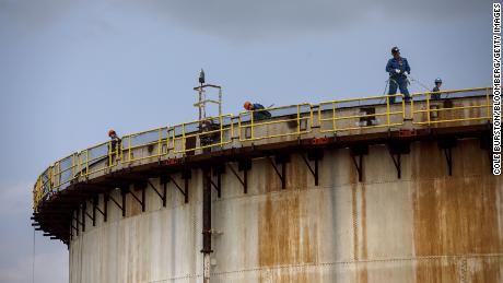 Workers stand atop a storage tank at an Imperial Oil Ltd. refinery near the Enbridge Line 5 pipeline in Sarnia, オンタリオ, カナダ.