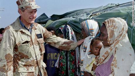 Then US President George H.W. Bush greets Somalian women while visiting US troops in Somalia in January 1993.