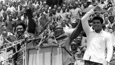 Zaire&#39;s President Mobutu Sese Seko (center) holds George Foreman (left) and Ali&#39;s arms aloft in Kinshaha on September 22, 1974 ahead of the fight dubbed &quot;The Rumble in the Jungle.&quot;