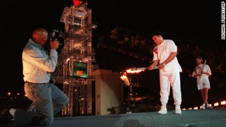 Muhammad Ali uses the Olympic torch to ignite the Olympic flame as swimmer Janet Evans, right, watches during the opening ceremony of the 1996 Summer Olympic Games in Atlanta, on July 19, 1996. 