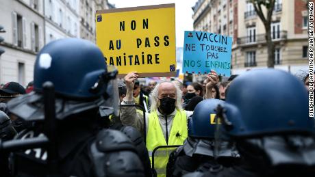 A protester holds signs reading, &quot;No to the health pass&quot; and &quot;Vaccine: keep away from our children,&quot; at a demonstration in the western Paris suburb of Neuilly-sur-Seine on August 7.